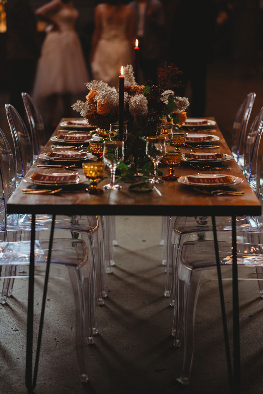 Wedding reception table with hairpin legs clear ghost chairs and amber tablescape decor » event rentals » Vogue.Rentals